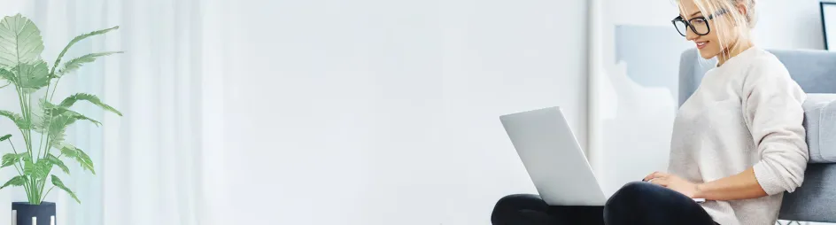 Bannerbild Frau sitzt gemütlich auf dem Sofa mit einem Laptop