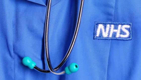 NHS logo on blue scrubs with a stethoscope 